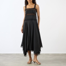Model wearing Ganni black silk blend midi dress with lace trim detail, handkerchief hem, and square neckline with wide straps