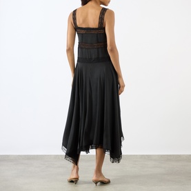 Model wearing Ganni black silk blend midi dress, rear view, featuring lace trim bodice and handkerchief hemline.