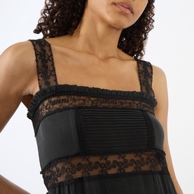 Model wearing Ganni black silk blend dress with lace panel bodice, ruffle trim and pleated sheer detail at waist