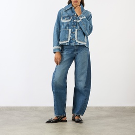 Model wearing Ganni Lace-Trim Denim Jacket in dark blue with lace detailing, styled with wide-leg jeans and black embellished flats.