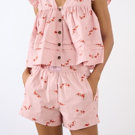 Model wearing Ganni pink floral cotton shorts with elasticated waist, styled with matching tiered ruffle top