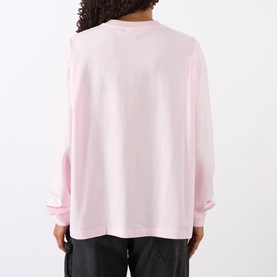 Model wearing Ganni Chalk Pink long-sleeve cotton sweat top, relaxed fit, rear view, styled with black trousers.