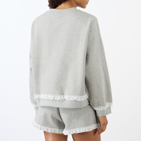 Model wearing Ganni Isoli Logo Lace-Trim Sweatshirt in Paloma with lace-hem detail, styled with matching shorts. Rear view.