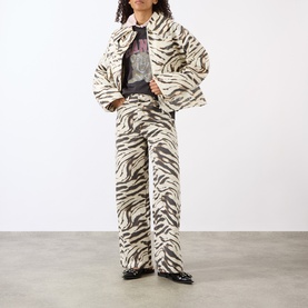 Model wearing Ganni Tiger Heavyweight Logo T-Shirt in Phantom, styled with matching tiger-print jacket and wide-leg trousers, black loafers.