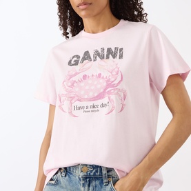 Model wearing Ganni Crab Logo T-Shirt in Chalk Pink with crew neck, dropped shoulders, and front crab graphic print, styled with light blue jeans.