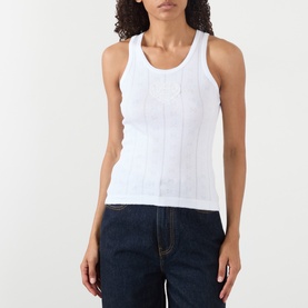 Model wearing Ganni Bright White cotton ribbed tank top with scoop neck and racerback, styled with dark denim jeans.