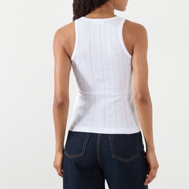 Model wearing Ganni Top in Bright White, sleeveless ribbed cotton design, shown from behind with dark denim jeans.