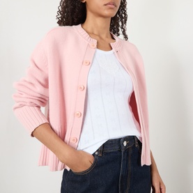 Model wearing Ganni Bright White cotton top with pink button-front cardigan and dark blue jeans