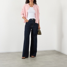 Model wearing Ganni Bright White cotton top, styled with pink jacket, dark wide-leg jeans, and olive mini bag.