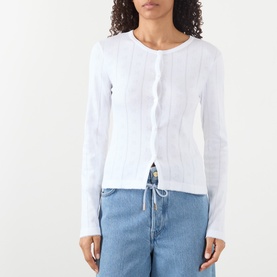 Model wearing Ganni Bright White cotton long-sleeve top with ribbed button-front detail, styled with light blue denim jeans.