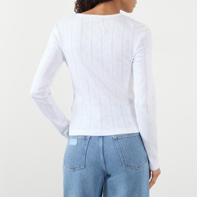 Model wearing Ganni Bright White cotton long-sleeve ribbed top, back view, styled with light blue wide-leg jeans