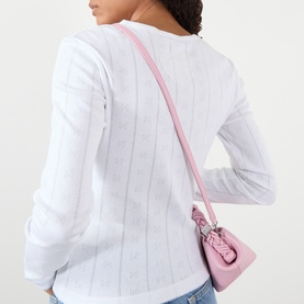 Model wearing Ganni Bright White cotton top, back view, styled with a pink crossbody bag and light blue jeans.