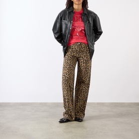 Model wearing Ganni Cherry Logo Baby Tee in High Risk Red, styled with leopard-print wide-leg trousers and an oversized black leather jacket.