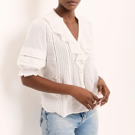 Model wearing Mint Velvet Ruffle Trim Blouse in white with V-neckline, pin tuck detail and crochet trim, styled with light blue jeans.