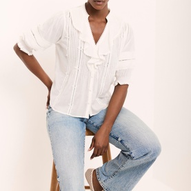 Model wearing Mint Velvet Ruffle Trim Blouse in white with V-neckline, pintuck detail and crochet trim, styled with light-wash jeans
