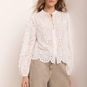 Model wearing Mint Velvet Shell Broderie Blouse in white with scallop trim and long sleeves, styled with grey trousers.