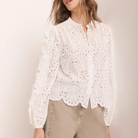 Model wearing Mint Velvet Shell Broderie Blouse in white with scallop hem, long sleeves, crew neckline, styled with beige trousers