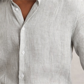 Model wearing Reiss white and thyme green pinstripe linen shirt, close-up detail of button placket and collarless neckline.
