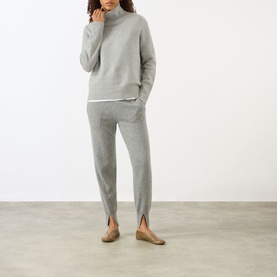Model wearing Lisa Yang Heidi Turtleneck Cashmere Sweater in Dove Grey, styled with matching grey knit trousers and taupe ballet flats.