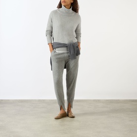 Model wearing Lisa Yang Heidi Turtleneck Cashmere Sweater in Dove Grey, styled with matching grey joggers and taupe flats