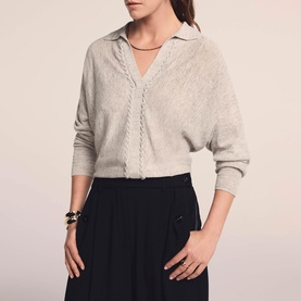 Model wearing Mint Velvet Cream Open Collar Trim Top with V-neckline and batwing sleeves, styled with black wide-leg trousers and gold bracelet.