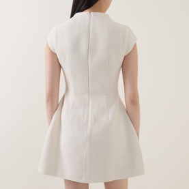 Model wearing Odd Muse Tweed Flap Pocket Mini Dress in cream, rear view showing zip fastening, fitted waist, and voluminous mini skirt.