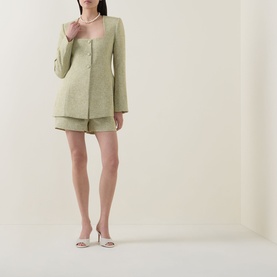 Model wearing Odd Muse green textured jacket with matching shorts, styled with pearl necklace and nude heeled sandals