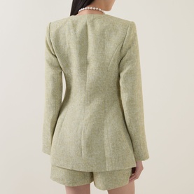 Model wearing Odd Muse green textured blazer, back view, styled with matching shorts and pearl necklace