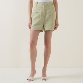 Model wearing Odd Muse green tweed shorts with patch pocket, styled with white strappy heeled mules.