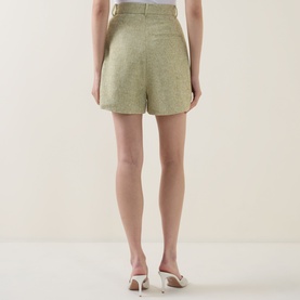 Model wearing Odd Muse green tailored shorts, rear view, styled with white heeled mules.