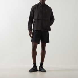 Model wearing On Running Espresso Casual Jacket with matching shorts and black trainers. Hooded, zip-front with chest pockets.