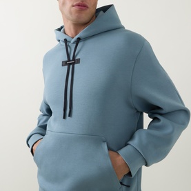 Model wearing On Running Hoodie in Agave, a muted blue-green with black drawstring detail and front kangaroo pocket.