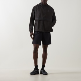 Model wearing On Running black performance shorts with matching black zip-up jacket and black trainers.