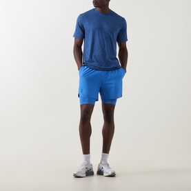 Model wearing On Running Jay Heather shorts with matching blue tee, white ankle socks and grey trainers.