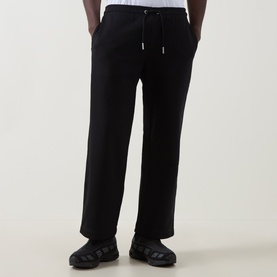 Model wearing On Running black sweatpants with drawstring waist and relaxed straight leg, styled with black trainers.