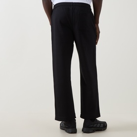 Model wearing On Running black sweatpants, wide-leg cotton-polyester blend, styled with white top and dark chunky-sole shoes, rear view