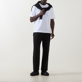 Model wearing On Running black sweatpants with white T-shirt, black scarf draped over shoulders and black trainers.