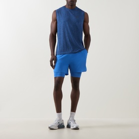 Model wearing On Running Jay Heather sleeveless T-shirt with matching blue shorts and white trainers.