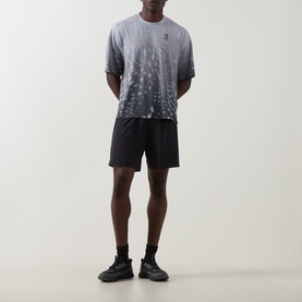 Model wearing On Running Espresso performance T-shirt with graphic print fade, styled with black shorts and black trainers.