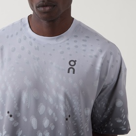 Model wearing On Running Performance T-Shirt in Espresso, showing geometric tonal pattern print and On logo at chest, close-up crop shot.