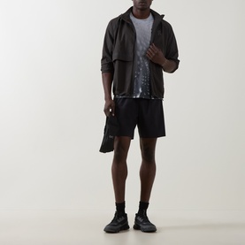Model wearing On Running Espresso T-Shirt with black zip-up jacket, black shorts, and black trainers.