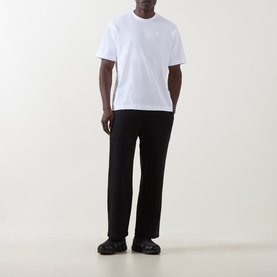 Model wearing On Running white cotton T-shirt with black straight-leg trousers and black trainers