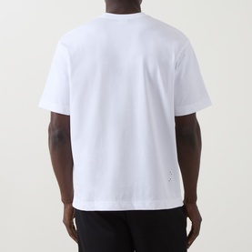 Model wearing On Running white cotton T-shirt, rear view, with small logo detail at lower back, styled with black trousers