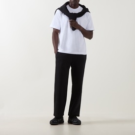 Model wearing On Running white cotton T-shirt with black scarf draped over shoulders, styled with black trousers and trainers.