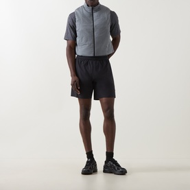 Model wearing On Running silver quilted performance gilet with black shorts and chunky black trainers.