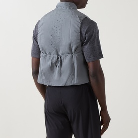 Model wearing On Running silver performance gilet, back view, styled with black trousers and short-sleeve shirt underneath