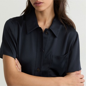 Model wearing Reiss blue short-sleeve shirt dress with collar and chest pocket, arms crossed.