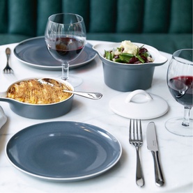 Royal Doulton slate Kitchenware Dinner Bowl styled on a dining table with plates, a lidded casserole, cutlery, and glasses of red wine.