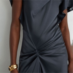 Model wearing Reiss slate grey dress with flutter sleeve detail and gathered twist front, styled with a gold cuff bracelet.