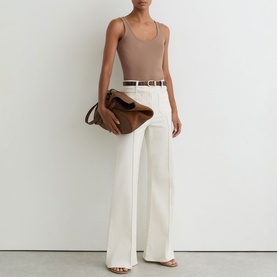 Model wearing Reiss taupe neutral bodysuit with white wide-leg trousers, white belt, and brown suede shoulder bag, nude heeled sandals.